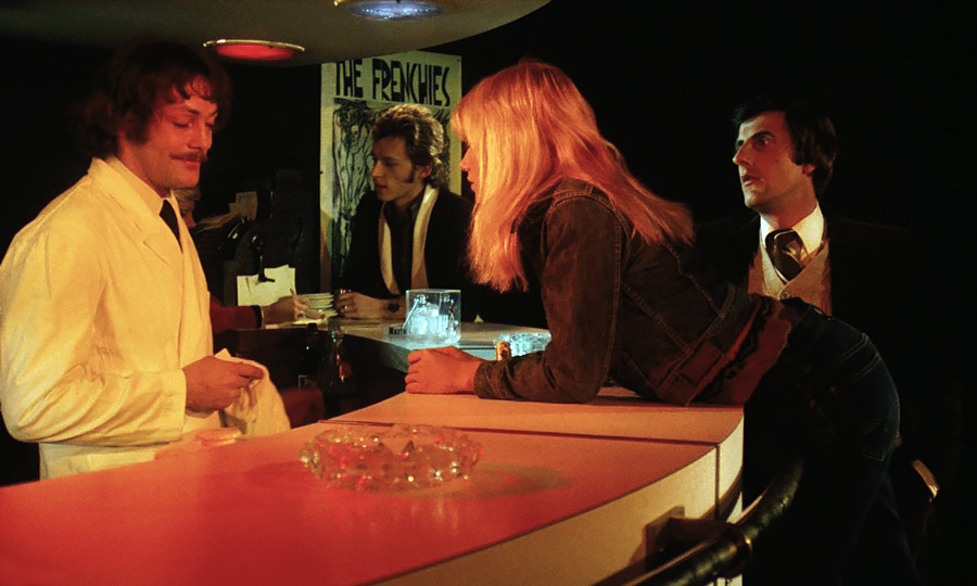 Deux autres clins d’œil de Georges Lautner dans Pas de problème ! : Patrick Dewaere qui apparaît en barman pour deux répliques et l’affiche des Frenchies, en background.